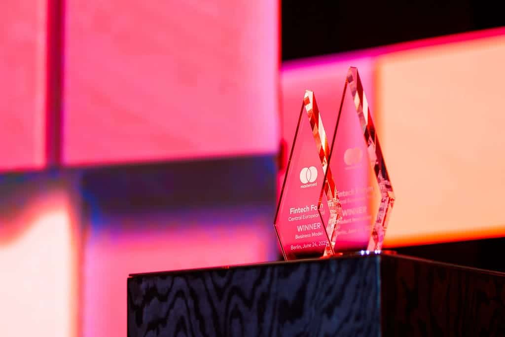 Vibrant pink fintech industry awards on black pedestal with illuminated background, celebrating innovation and success.