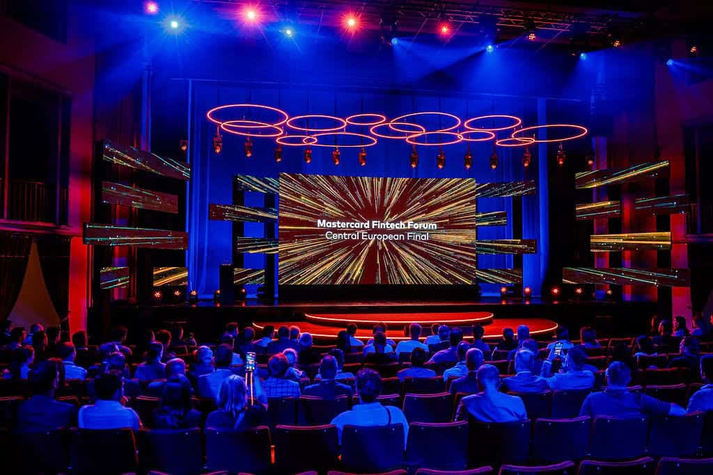Dynamic digital conference stage at Mastercard Fintech Forum with vibrant lighting and large LED screens.