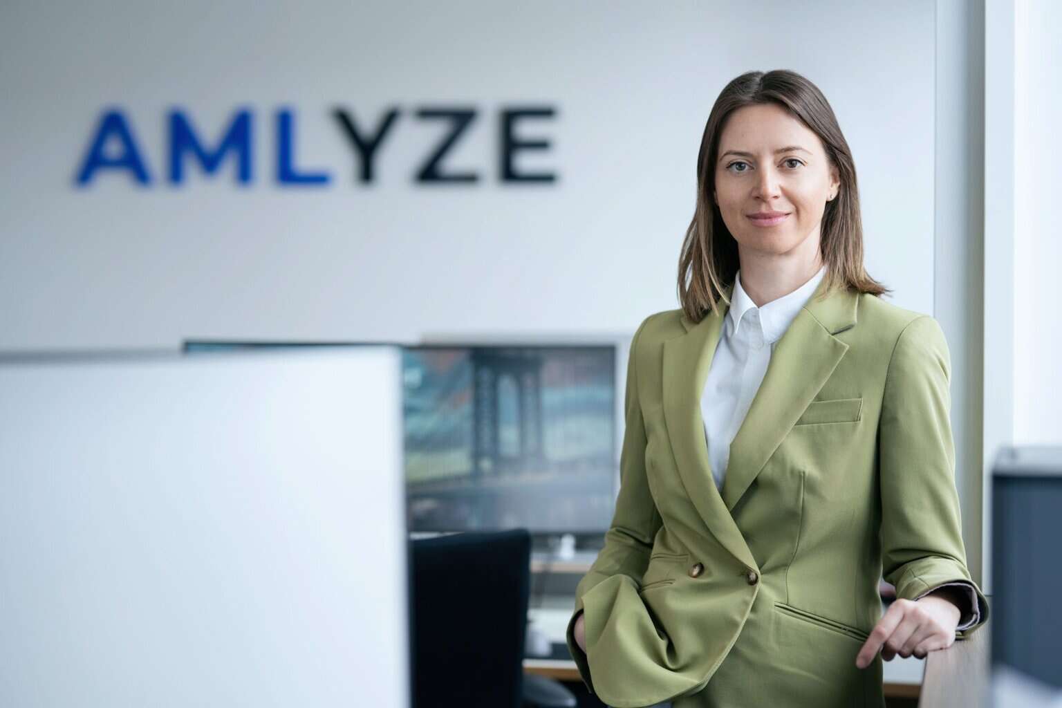 AMLYZE logo and a professional woman in business attire at modern office background.