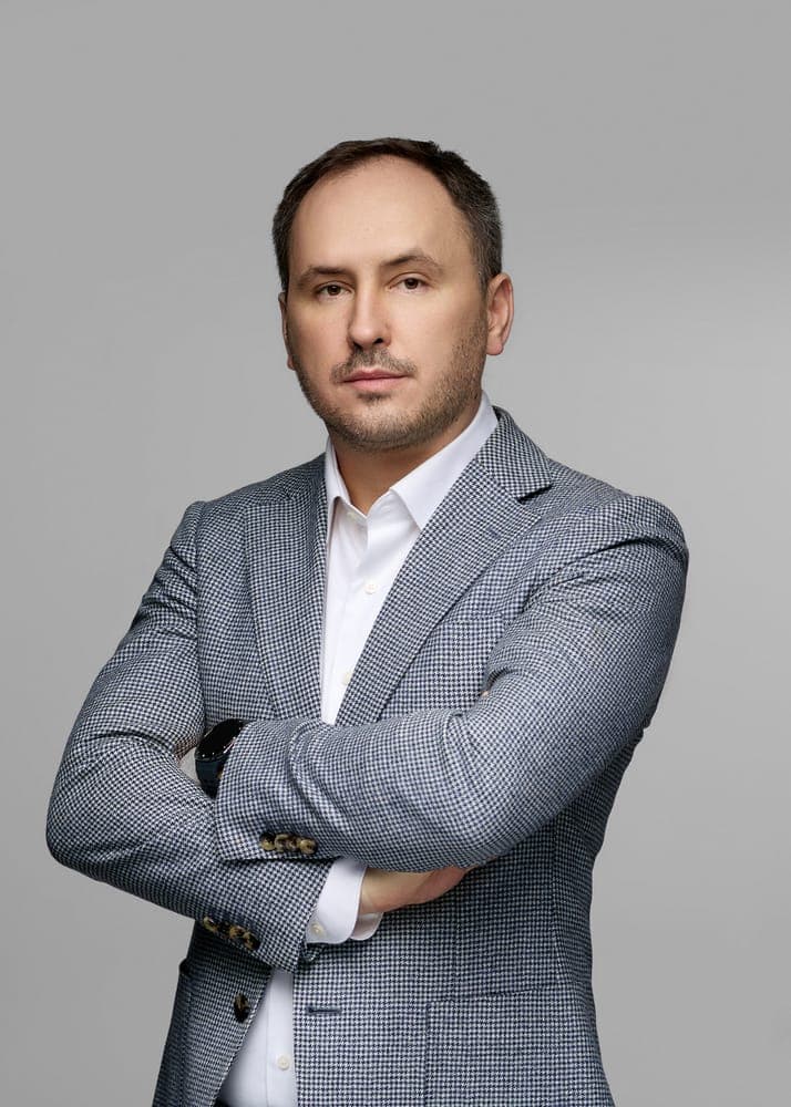 Professional businessman in a gray checkered suit with arms crossed, confident pose for AMLYZE SEO images.